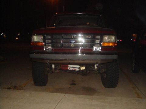 1992 Ford Bronco - Front view of a red 1992 Ford Bronco parked at night, showing its grille and headlights.
