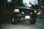 1995 Ford Bronco - This lifted black Ford Bronco is viewed from the front, showing its modified grille and lighting.