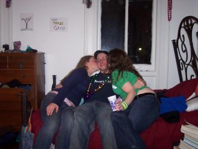 1997 Ford Crown Victoria - A man is kissed by two women while wearing Mardi Gras beads, with "Mardi Gras!" visible on the wall.