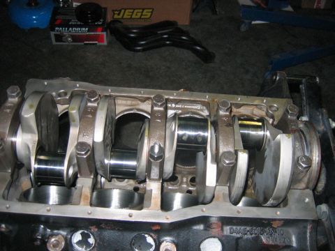 1992 Ford Mustang - Close-up of an engine's crankshaft and connecting rods, with automotive parts in the background.