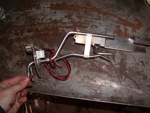 1991 Ford Bronco - Fuel pump assembly removed from a vehicle, resting on a metal surface.