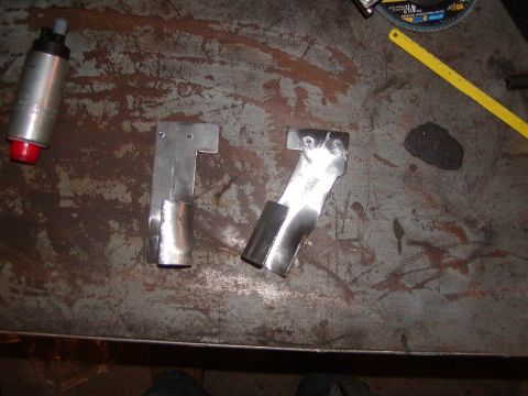 1991 Ford Bronco - A silver fuel pump and two metal brackets are laid out on a workbench surface.
