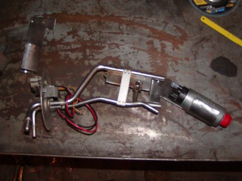 1991 Ford Bronco - A disassembled fuel pump assembly, metal tubing and electrical connectors, rests on a workbench.