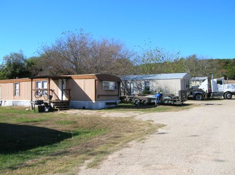 1996 Ford Bronco - A white semi-truck and trailer are parked in a lot with several mobile homes under a clear blue sky.