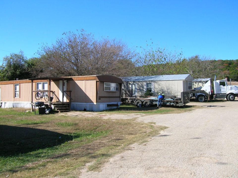 White semi-truck and trailer parked near mobile homes