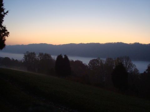 1995 Ford Bronco - A misty morning scene unfolds with rolling hills and trees silhouetted against a dawn sky.