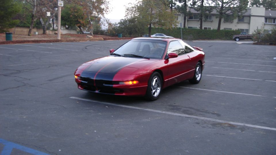 Red 1996 Ford Probe with black racing stripes parked in a lot