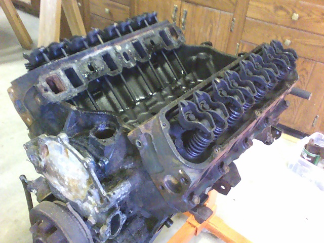 Engine block with valve covers removed, showing pistons and valve train