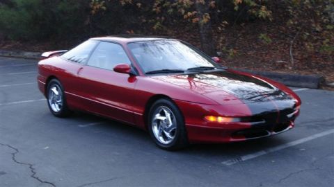 1996 Ford Probe - This red coupe with a black hood and spoiler is parked outdoors.