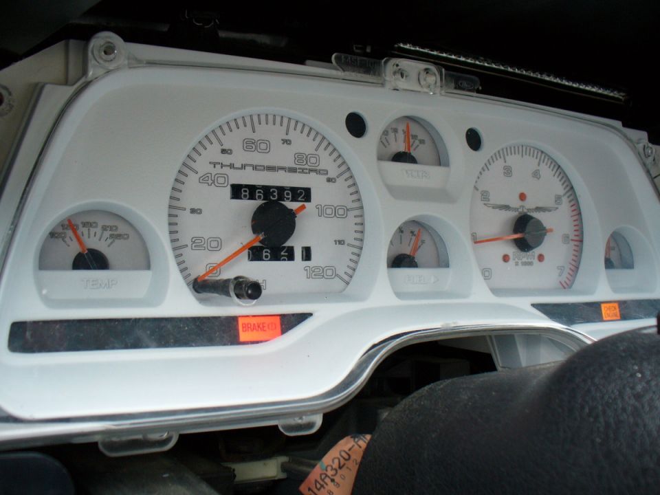 White car dashboard with 'THUNDERBIRD' text on speedometer, showing 86392 miles and a lit 'BRAKE' warning light