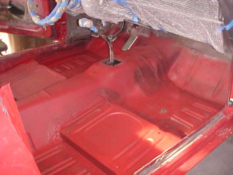 1967 Mercury Cougar - The interior of a car shows red-painted floor pans and the transmission tunnel, with some dashboard elements covered.