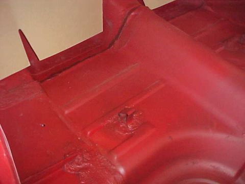 1967 Mercury Cougar - Close-up view of the red-painted interior floor pan, showing structural reinforcements and mounting points.