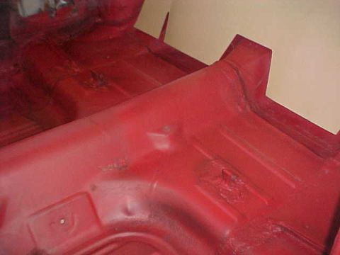 1967 Mercury Cougar - Interior floor pan of a car, painted red, showing some signs of wear and rust.