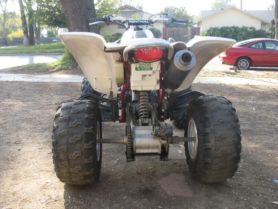 Rear view of white sport ATV quad parked on dirt outdoors