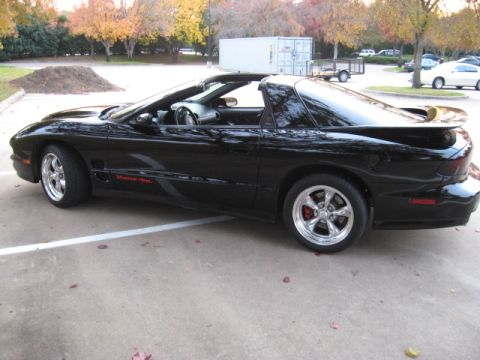 2002 Pontiac Trans Am - A black 2002 Pontiac Trans Am convertible is parked in a lot with autumn trees in the background.