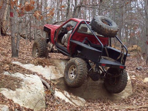 1978 Ford Bronco - Custom off-road vehicle navigates a rocky trail in a wooded area.