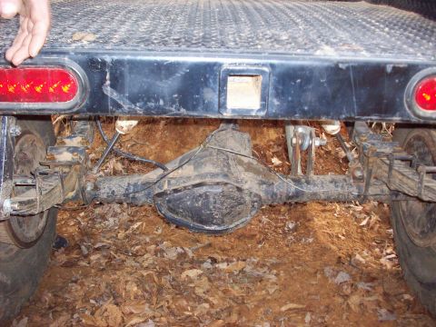 1978 Ford Bronco - The rear axle and leaf springs of a vehicle are visible, covered in mud and dirt.