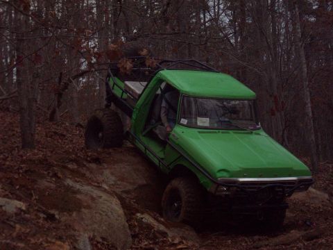 1978 Ford Bronco - Modified truck navigates a challenging off-road course through a wooded area.