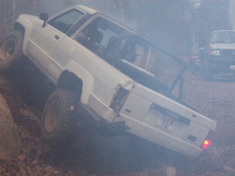 1978 Ford Bronco - A white Toyota pickup truck navigates a challenging off-road terrain with a second vehicle in the distance.