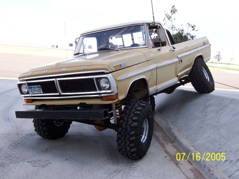 1994 Ford Bronco - This lifted Ford pickup truck is shown with its front wheels on a concrete incline, demonstrating its off-road capabilities.