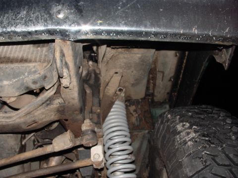 1979 Ford Bronco - Close-up view of a vehicle's undercarriage, revealing suspension parts and a tire, with visible frame damage.