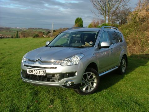 2007 Citroen C-Crosser - A silver 2007 Citroen C-Crosser is parked on a grassy slope with a wooded area in the background.