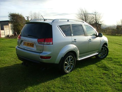 2007 Citroen C-Crosser - Rear 3/4 view of a silver SUV parked on a grassy field. The license plate reads BK99 AGB.