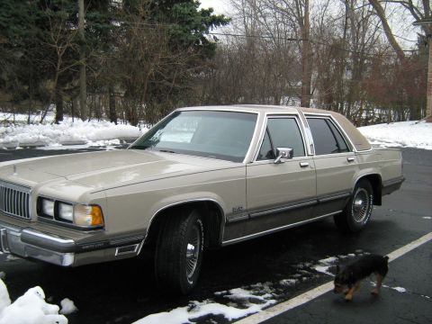 1988 Mercury Grand Marquis - A tan 1988 Mercury Grand Marquis sedan is parked on an asphalt lot with snow on the ground.