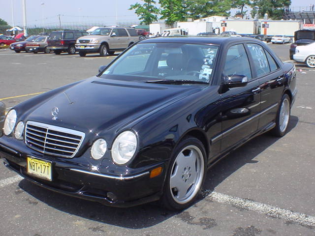 Black Mercedes-Benz E-Class sedan with racing stickers on windshield
