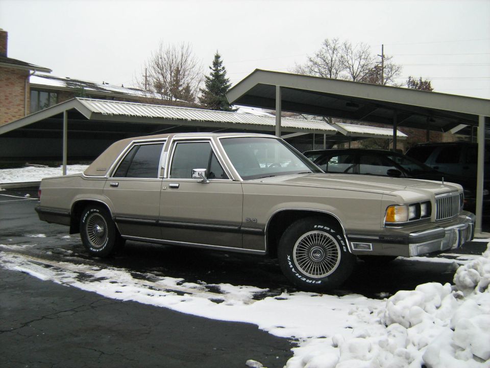 Tan 1988 Mercury Grand Marquis parked in a snowy lot under a carport