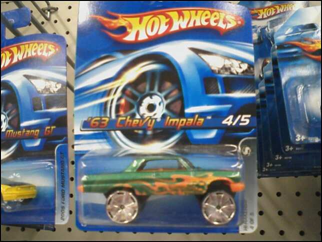 Carded Hot Wheels '63 Chevy Impala die-cast in green with orange flames on store pegboard