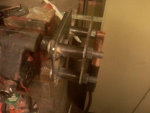 2001 Ford F-150 - A close-up view of a metal bracket assembly, secured in a vise, multiple bolts and nuts.