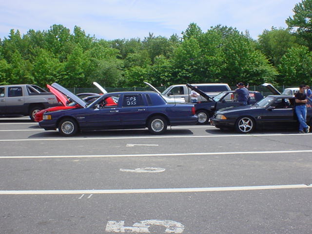 Dark blue sedan with hood open, parked on asphalt. Text on door reads '203 DAS'