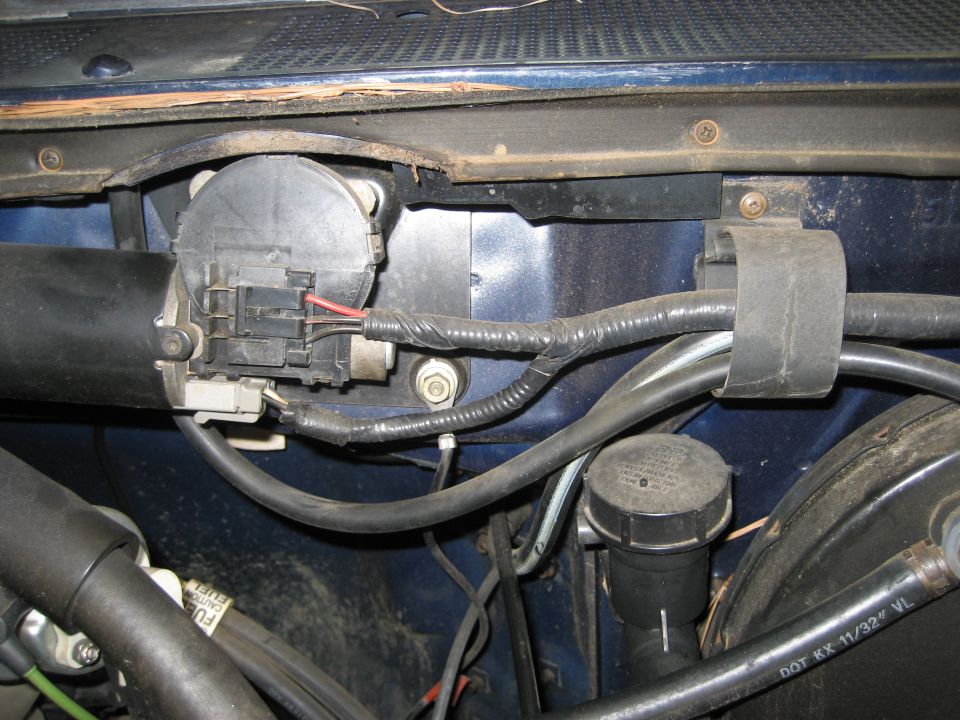 Close-up of a vehicle's windshield wiper motor and wiring harness