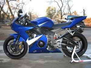 2005 Yamaha R1 - A blue motorcycle is parked outdoors, with a watermark from SUPERMOTORS.NET visible on the lower right.