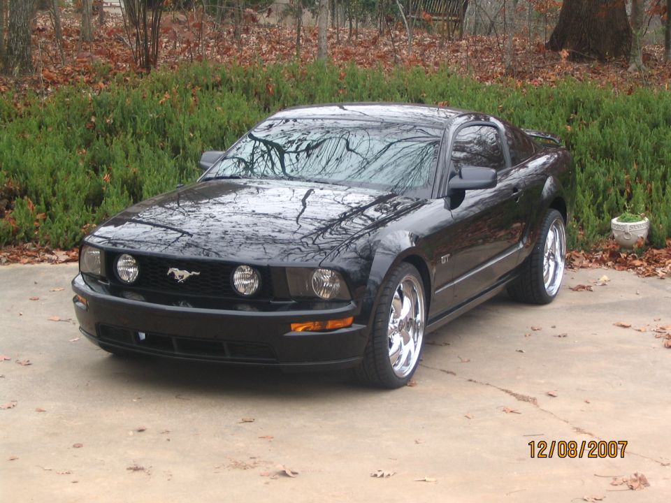 Black 2007 Ford Mustang GT coupe with chrome wheels parked on a driveway