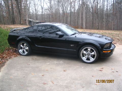 2007 Ford Mustang - A black 2007 Ford Mustang GT coupe is shown from a three-quarter front angle on a concrete driveway.