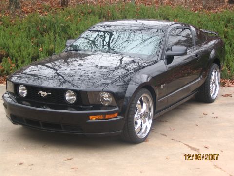 2007 Ford Mustang - A black 2007 Ford Mustang GT is shown from the front three-quarter view, custom chrome wheels.