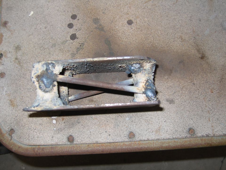 Welded metal part with internal bracing, resting on a textured surface