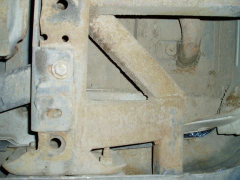 2000 Ford E350 - Undercarriage view of heavily corroded metal frame components and fasteners.