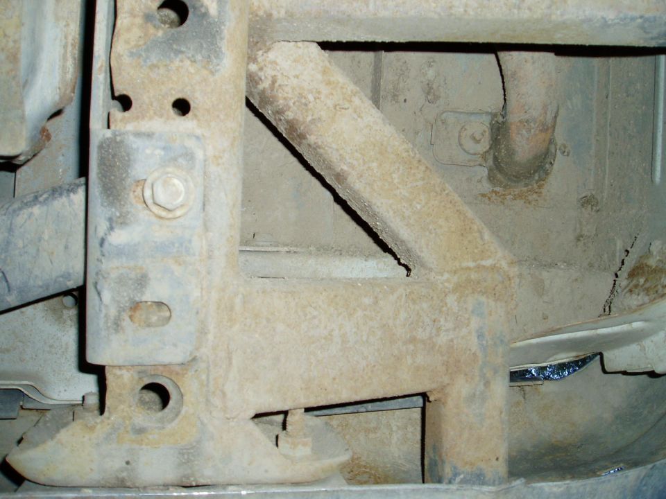 Close-up of heavily rusted metal frame and bracketry with bolts