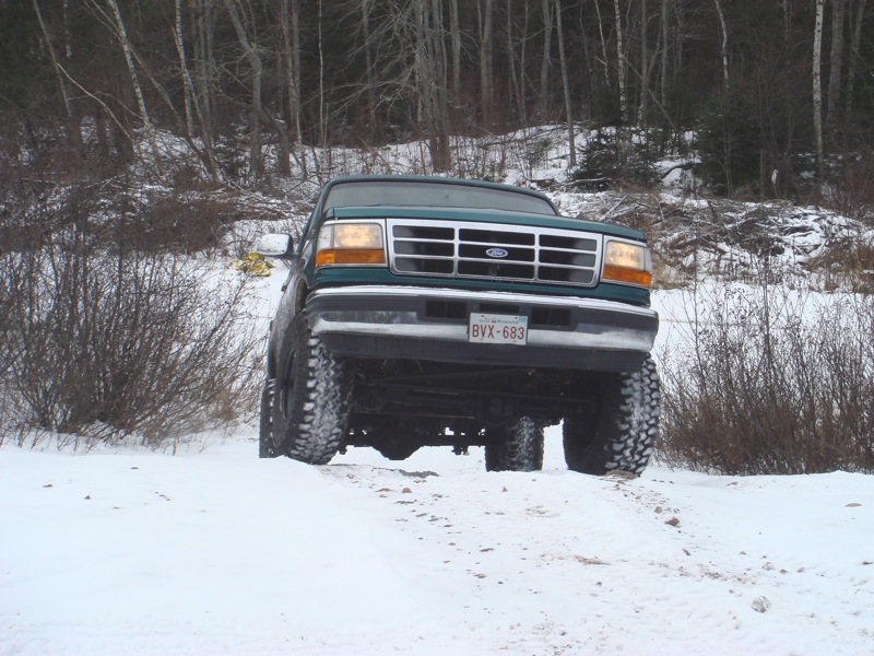 Green Ford truck with lifted suspension driving in snow. License plate BVX-683