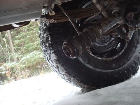 1996 Ford Bronco - Undercarriage view of a vehicle's driveshaft boot and tire, covered in snow and mud.