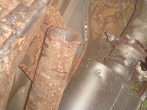 1996 Ford Bronco - Close-up view of a heavily rusted exhaust pipe and muffler, indicating significant wear and tear.