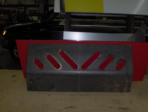 1978 Ford Bronco - A fabricated metal skid plate with multiple angled slots is shown in a workshop setting.