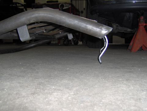 1978 Ford Bronco - A close-up view of a bent exhaust pipe with a piece of metal hanging from it.