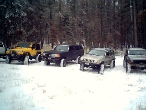 1990 Ford Bronco - A group of four-wheel-drive vehicles are parked in a snow-covered wooded area.