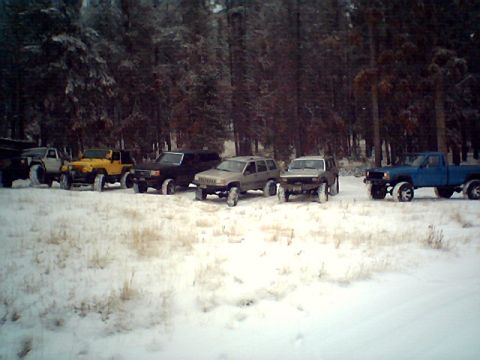 1990 Ford Bronco - A group of off-road vehicles are parked in a snow-covered forest.