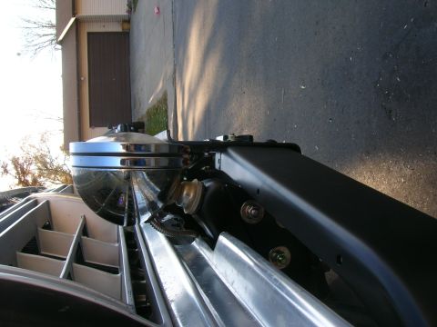 1979 Ford Bronco - Close-up view of a chrome headlight assembly and grille detail on a vehicle part.
