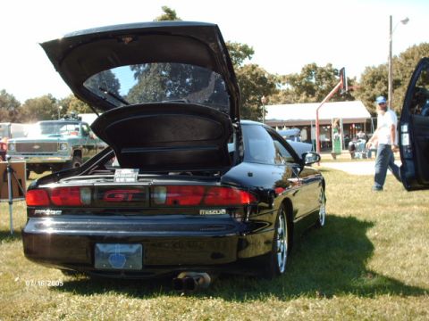 1995 Ford Probe - A black Mazda Probe GT is parked on a grassy field with its trunk and driver's door open.
